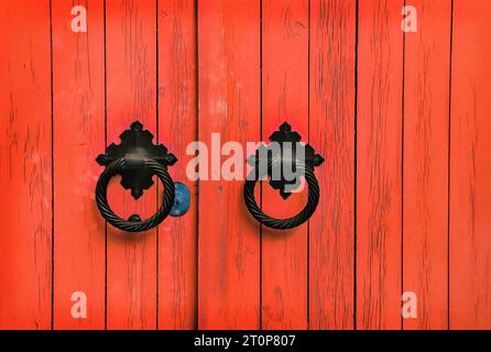 Porta in legno rosso brillante con maniglie rotonde Foto Stock