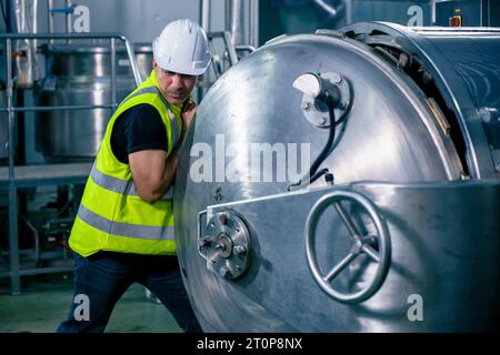 Tecnico ingegnere lavoratore maschio che lavora nella sala caldaia per il controllo della routine di manutenzione del tubo del gas nella fabbrica industriale Foto Stock