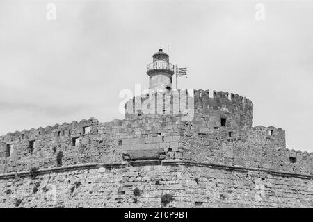 Primo piano della fortezza di San Nicola, torre rotonda con faro e bandiera nazionale greca in bianco e nero Foto Stock