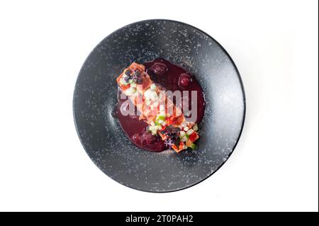 Tataki di salmone in salsa di ciliegia su un piatto nero isolato. Foto di alta qualità Foto Stock