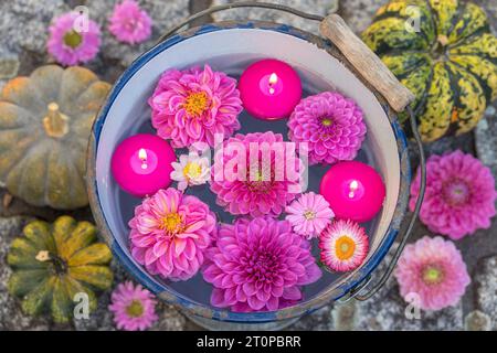 sistemazione romantica con candele galleggianti e fiori dahlia rosa in secchiello vintage Foto Stock