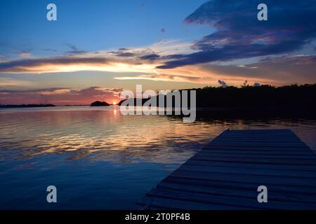 Un bellissimo tramonto sul lato laguna di San Pedro, Belize. Le nuvole e le sfumature blu si riflettono nell'acqua. Foto Stock