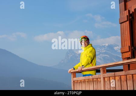 Lo sciatore ammira il panorama delle Alpi dal balcone dello chalet Foto Stock