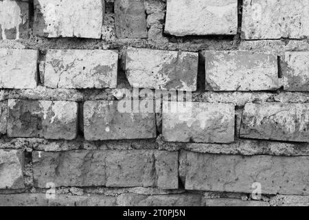 Un frammento di un vecchio muro abbandonato, primo piano, di colore grigio. Immagine in bianco e nero. Sfondo astratto del muro di mattoni. Foto Stock