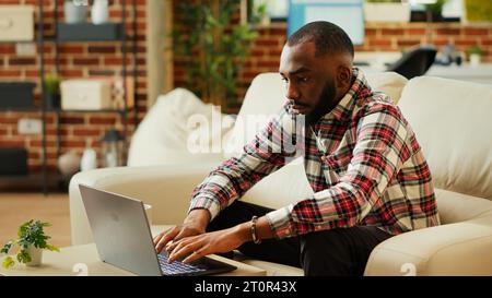 Lavoratore remoto che si occupa di svolgere attività lavorative in un accogliente e moderno ufficio personale. Telelavoro freelance da casa, digitazione sulla tastiera e sorriso alla fotocamera, primo piano al rallentatore Foto Stock