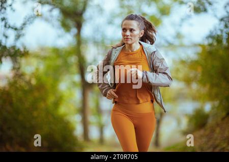 Ciao autunno. vesti la donna con i vestiti per il fitness nel parco che corre. Foto Stock