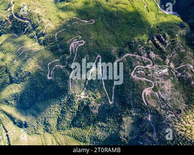 Dall'occhio di un drone, il panorama aereo dell'Urique Canyon all'interno del Copper Canyon, Chihuahua svela una strada tortuosa che conduce al villaggio annidato di Uriq Foto Stock