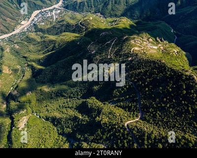 Dall'occhio di un drone, il panorama aereo dell'Urique Canyon all'interno del Copper Canyon, Chihuahua svela una strada tortuosa che conduce al villaggio annidato di Uriq Foto Stock