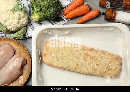 Delizioso strudel con pollo e verdure su un tavolo di legno grigio, piatto Foto Stock