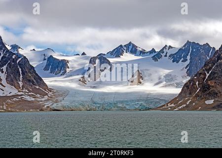 Ghiacciaio Tidal e Snowy Mountains nell'alto Artico nelle Isole Svalbard in Norvegia Foto Stock