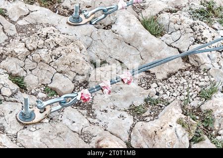 Fissaggio dei sostegni a ponte sospesi nella roccia con grandi tasselli in metallo per primo piano. Attrezzatura di supporto avvitata nelle pietre del parco per arrampicate di montagna Foto Stock