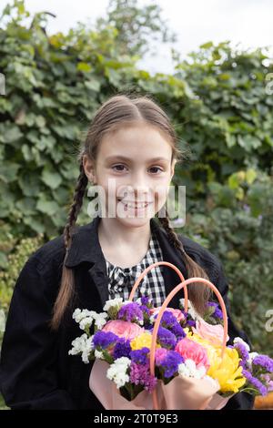 ritratto di una felice bambina di 8 anni con un bouquet di fiori multicolore. bambini emotivi gioiosi, bambini positivi, umore festivo. Omaggio di fiori per Foto Stock