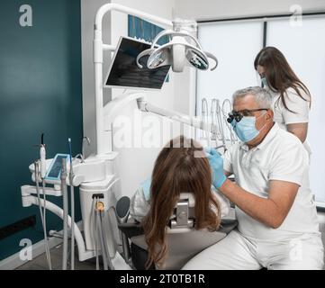 Metodi moderni di trattamento della carie e di altre malattie della cavità orale nella clinica. Il paziente può fidarsi del dentista con l'assistente dentale Foto Stock