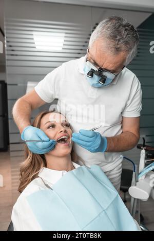 Il paziente dimostra fiducia nel dentista durante le procedure mediche. Una donna riceve cure e consigli su cure dentistiche professionali. Foto Stock