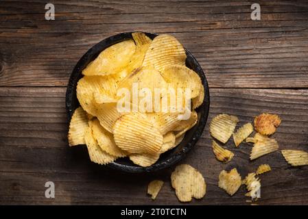 Patatine croccanti in un recipiente su uno sfondo di legno Foto Stock