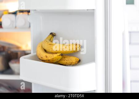 Primo piano delle banane sullo scaffale nel contenitore aperto del frigorifero. Foto Stock