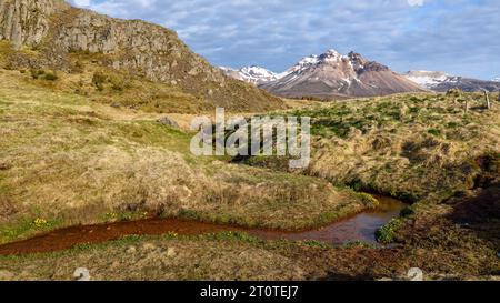 Splendido paesaggio imontano a Bakkagerdi ("Bakkagerði" in islandese) nell'Islanda orientale. Sfrecciare in montagna attraverso un prato erboso. Foto Stock