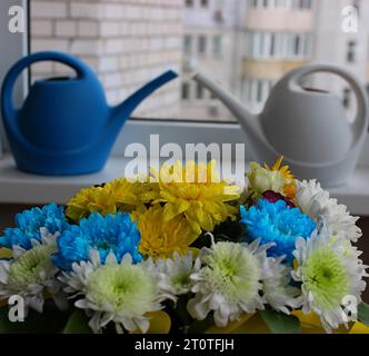 Annaffiatoi in plastica bianco e blu su davanzale con fori in primo piano Foto Stock