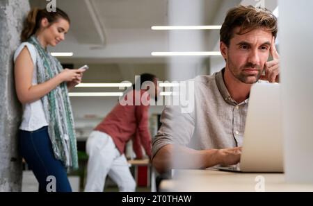 Lavoro stressante. Stressato giovane uomo d'affari che lavora con un computer portatile e ha problemi sul posto di lavoro. Foto Stock