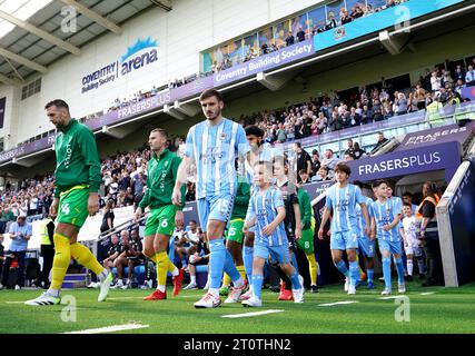 Liam Kitching di Coventry City si fa strada con una mascotte del giorno della partita in vista del match per il campionato Sky Bet alla Coventry Building Society Arena di Coventry. Data immagine: Sabato 7 ottobre 2023. Foto Stock