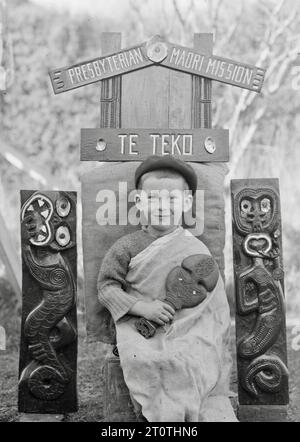 Albert Percy Godber (fotografo neozelandese) - nipote Colin, seduto sotto un cartello scolpito per la missione presbiteriana Maori a te Teko - c1938 Foto Stock