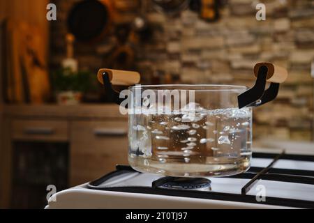 Acqua bollente in pentola di vetro trasparente sul piano cottura Foto stock  - Alamy