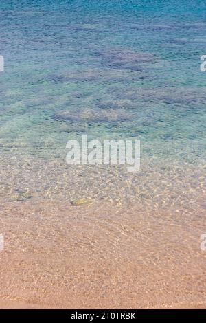 L'acqua limpida della spiaggia della baia di St Paul crea una sfumatura turchese e marrone Foto Stock