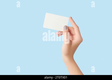 Mani femminili curate che tengono un biglietto da visita su sfondo grigio in cemento Foto Stock