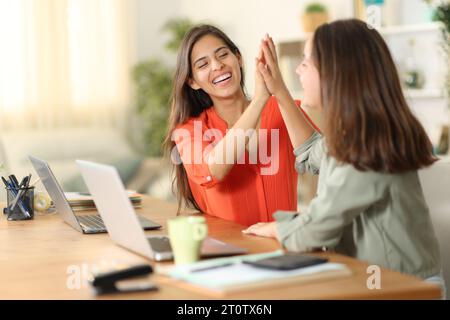 Due telelavoratori che ne danno cinque per celebrare il successo a casa Foto Stock