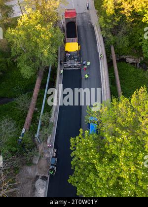 Vista aerea della costruzione di una nuova strada, con asfaltatrici, rulli, macchinari e lavoratori che si uniscono per costruire un collegamento di trasporto vitale. W Foto Stock