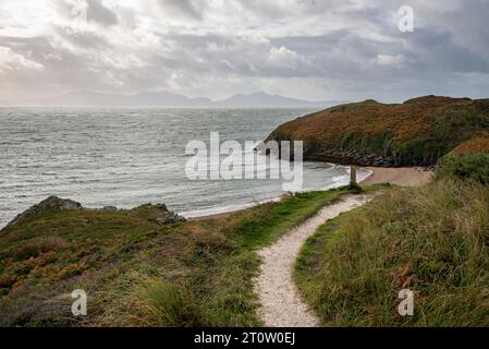 Sentiero costiero sull'isola di Llanddwyn, Anglesey, con vista sulla terraferma gallese in una luminosa e ventilata giornata autunnale. Foto Stock