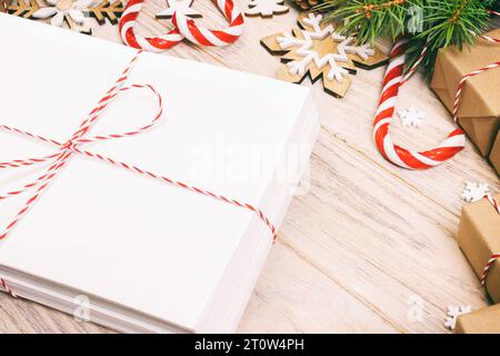 Busta con foglio di carta bianco su sfondo di Natale - ramo di abete, pigne, nastro rosso, stella e il cuore di dolci. Spazio per il testo. Tonica. Foto Stock