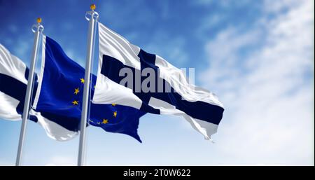 Bandiere nazionali della Finlandia che sventolano al vento con la bandiera dell'Unione europea in una giornata limpida. rendering dell'illustrazione 3d. Tessuto ondulato Foto Stock