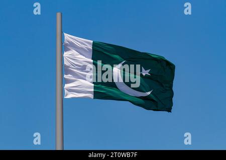 Bandiera del Pakistan che sventola nel vento su un palo contro il cielo blu Foto Stock