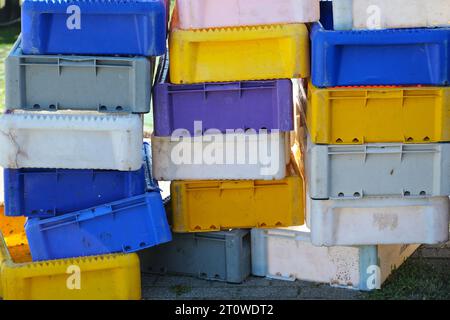 Pila di casse di plastica in blu, giallo e bianco per il trasporto e la vendita di pesce sul mercato nel porto di pesca, concetto commerciale e industriale Foto Stock