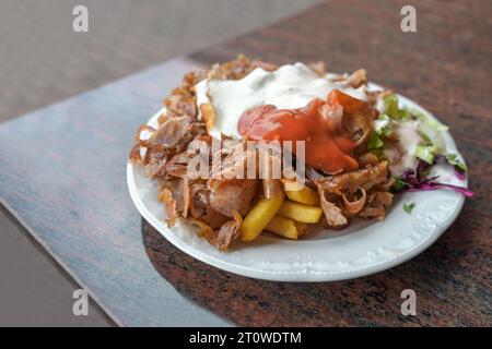 Piatto di kebab Doner con carne, patatine fritte, insalata e due salse serviti in un fast food turco in Germania, spazio per la copia, attenzione selezionata, molto Foto Stock