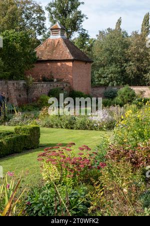 Varietà di arbusti e fiori che riflettono il sole del tardo pomeriggio in autunno, presso l'Eastcote House, storico giardino murato nel Borough di Hillingdon, Regno Unito Foto Stock