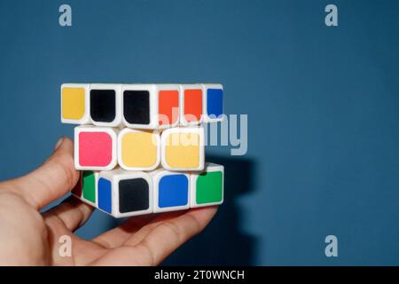 Foto di una persona che regge un rubik su sfondo azzurro Foto Stock