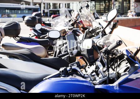 Diverse motociclette e ciclomotori di tutti i tipi parcheggiati in fila su un marciapiede in una città europea Foto Stock