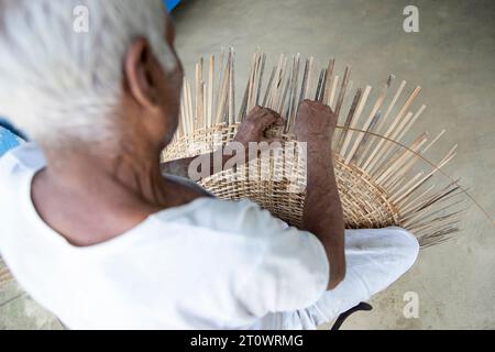 Un uomo anziano che tesseva cestino di strisce di bambù ecologiche, Majuli, Assam, India nordorientale, Asia Foto Stock