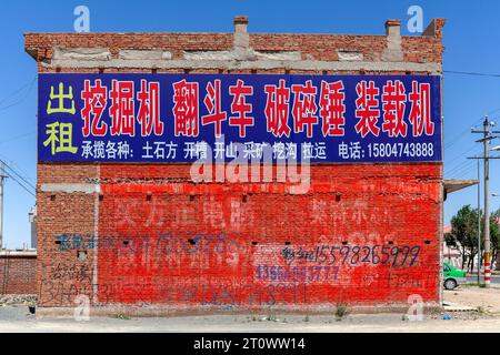 Edificio decorato da annunci lungo una strada nelle praterie di Gegentala a nord di Hohhot nella Mongolia interna, Cina Foto Stock