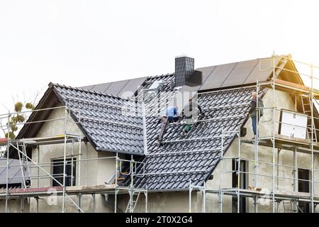Lavoratori che installano pannelli solari sul tetto di un'unica casa familiare Foto Stock