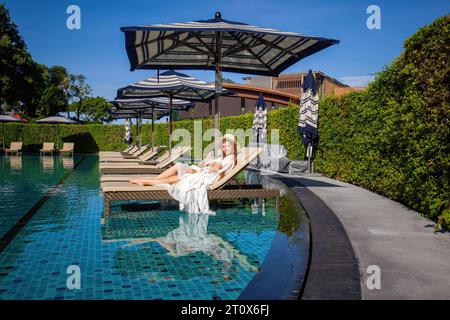 Donna, vestita elegantemente di bianco, trova relax in un paradiso tropicale Foto Stock