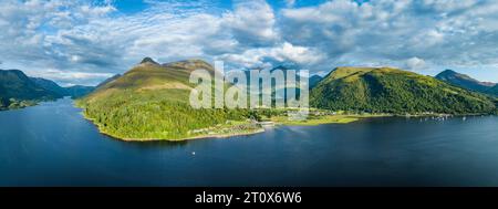 Panorama aereo del lago d'acqua dolce loch Leven con il villaggio di Glen Coe, sopra di esso, il Pap of Glencoe, Highlands, Scozia, alto 742 metri Foto Stock