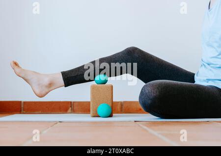 Muscolo del vitello sulla sfera di massaggio di terapia sul blocco di sughero per il rilascio miofasciale e l'idratazione. Concetto: Pratiche di cura di sé a casa, sollievo dal dolore del piede Foto Stock