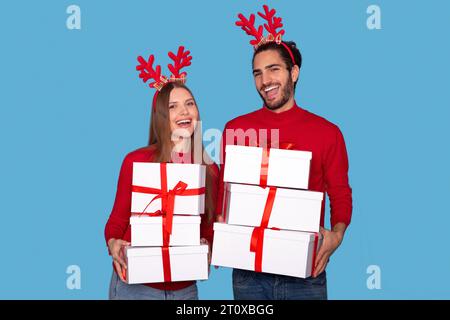 Coppia giovane gioiosa che indossa le corna delle Antlers per la festa delle renne con regali di Natale Foto Stock