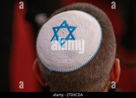 Berlino, Germania. 9 ottobre 2023. Un partecipante alla preghiera commemorativa e di solidarietà per Israele si trova avvolto in una bandiera di Israele con indosso un kippah con la Stella di Davide. Crediti: Monika Skolimowska/dpa/Alamy Live News Foto Stock