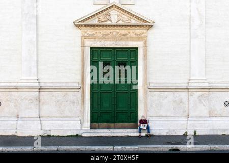 Roma, Italia-11 giugno 2023; uomo che legge il giornale seduto sui gradini di fronte alla porta della chiesa nostra Signora del Sacro cuore Foto Stock