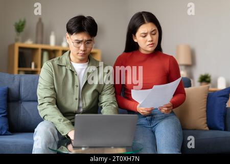 Depressa coppia giapponese che esamina le bollette che calcolano il budget a casa Foto Stock