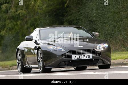 Bicester, Oxon., UK - 8 ottobre 2023: 2012 ASTON MARTIN VVANTAGE V12 auto d'epoca che guida su una strada di campagna inglese. Foto Stock